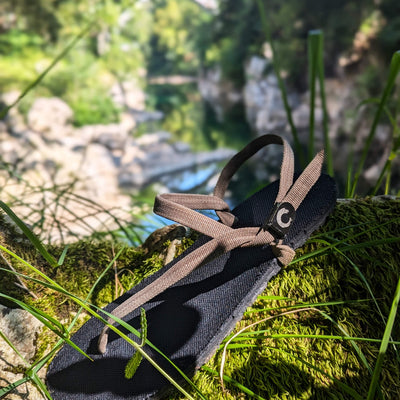ZuZu Flex barefoot performance sandals with a breathable canvas footbed and replaceable recycled desert straps, designed for natural movement and all-day comfort. Beautiful creek view.