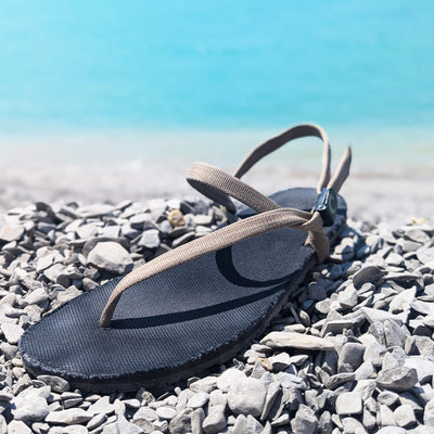ZuZu Flex barefoot water performance sandal with a breathable canvas footbed and replaceable recycled straps, designed for natural movement and all-day comfort. On a rock in the river-daycomfort.Byanamazinglake